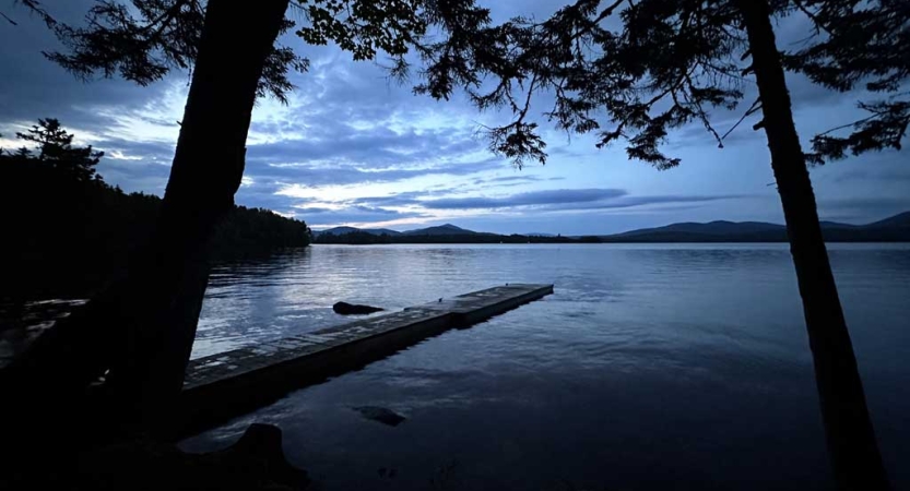 The sky appears in gentle colors above trees and a body of water. 